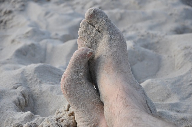 pies manchados de arena en la playa